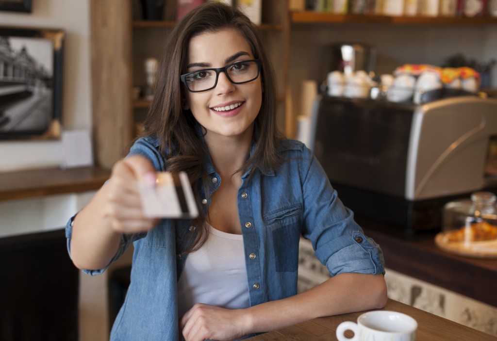 Smiling woman paying for coffee by credit card