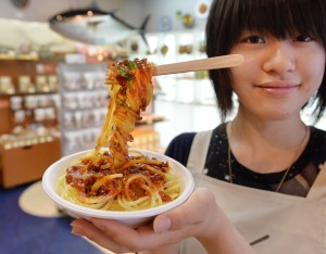 TO GO WITH Japan-culture-food-lifestyle,FEATURE by Kyoko HASEGAWA This photo taken on May 28, 2013 shows a shop cerk of a plastic food maker displaying a bowl of spaghetti with a spoon, all made of plastic, in Tokyo.  The company opened two shops in Tokyo where it sells sushi cell-phone charms and bacon-adorned key chains -- all with multilingual signs warning that "this is not edible".  The shops also let visitors take a stab at creating their own fake food.      AFP PHOTO / KAZUHIRO NOGI