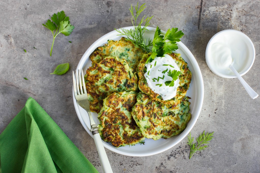 zucchini fritters, vegetarian zucchini pancakes, served with fresh herbs and garlic yogurt sauce, top view