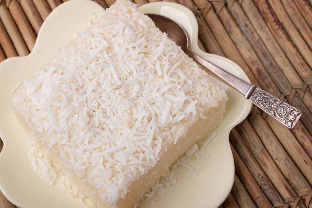 Brazilian traditional dessert: sweet couscous (tapioca) pudding (cuscuz doce) with coconut on wooden board. Selective focus
