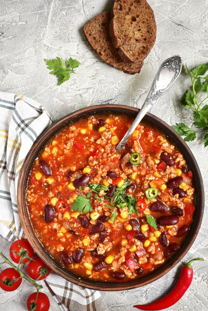 Chili con carne in a clay bowl on a concrete or stone rustic background- traditional dish of mexican cuisine.Top view.