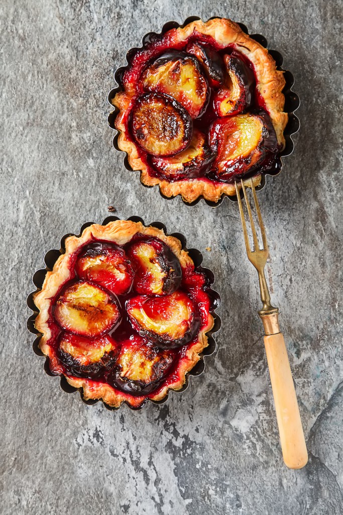 Homemade cake tartlets with plum  old stone background