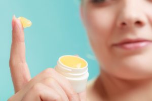 Female putting applying lip balm moisturizing balsam. Girl taking care of lips. Skincare.