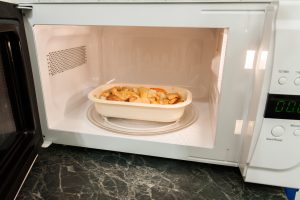 View of open microwave oven with delivery service food inside