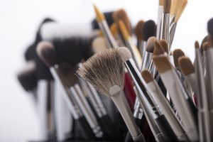 Closeup of different professional natural soft make-up brushes for eyeshadow powder and facial foundation for visagistes black and brown colors on white background, horizontal picture