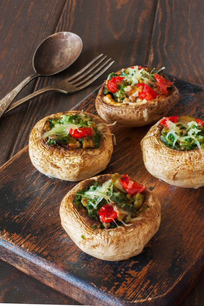 Mushrooms stuffed with vegetable mince and cheese served on the old cutting board