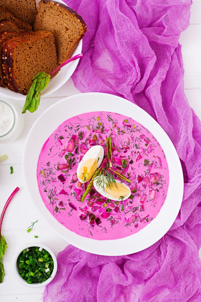 Cold beetroot (beet) soup on yogurt with egg, onion and cucumbers. Flat lay. Top view.